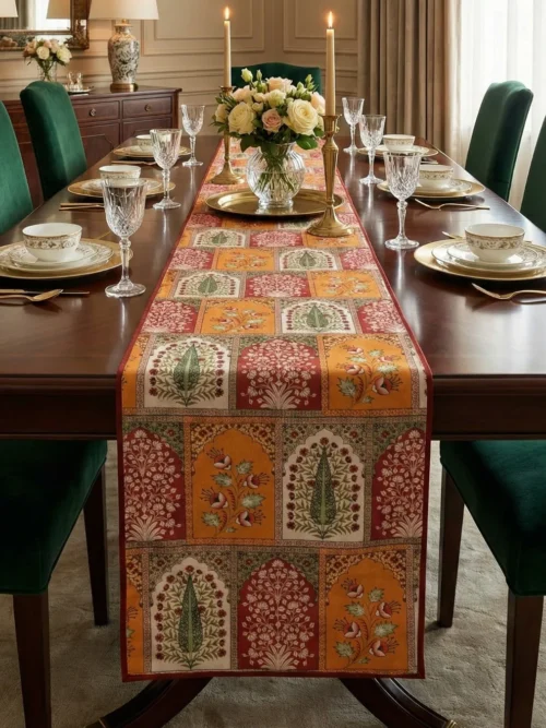 Mughal floral patch table runner placed on a wooden dining table with upholstered green chairs